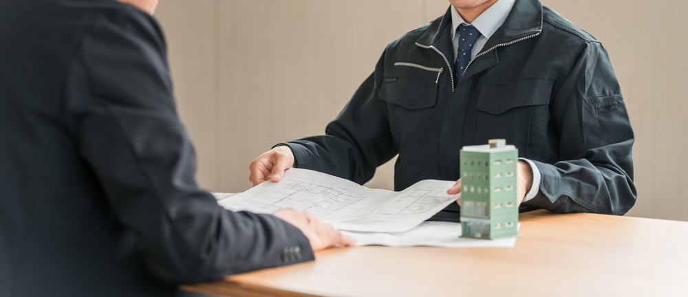 図面を挟んで打ち合わせをする管理会社の担当者と管理組合の理事